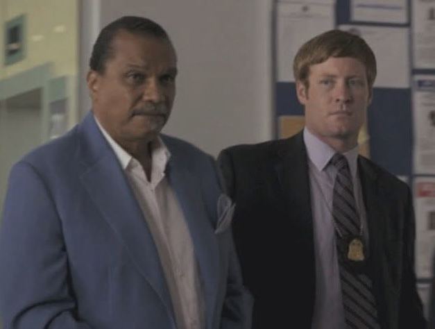 A White Collar scene with Chris McGuire as an FBI background performer beside Billy Dee Williams.